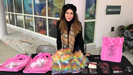 Angela Zervos posing in front of items on a table at the Shepherd Center Food and Supplies Fundraiser