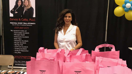 Angela Zervos posing in front of pink bags at the Shepherd Center Food and Supplies Fundraiser