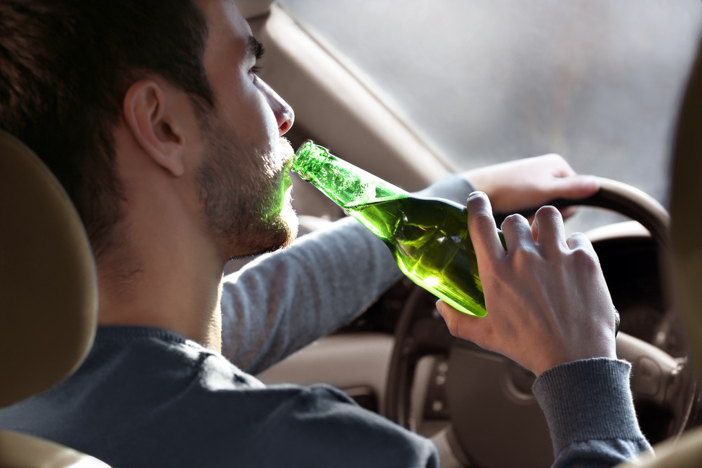 Driver is drinking beer while driving.