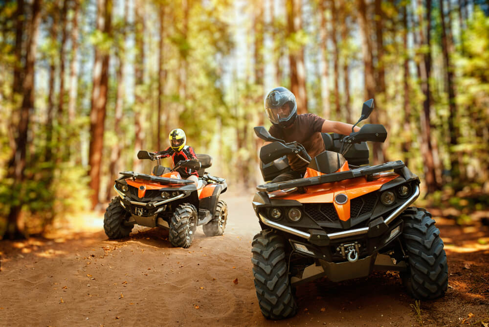 Two atv riders, speed race in forest.